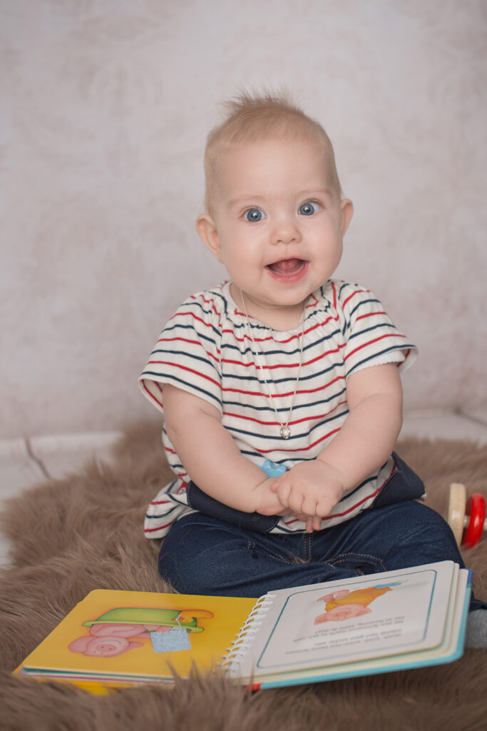 Baby sitzt und blättert in einem Bilderbuch – Babyfotoshooting Ludwigsburg