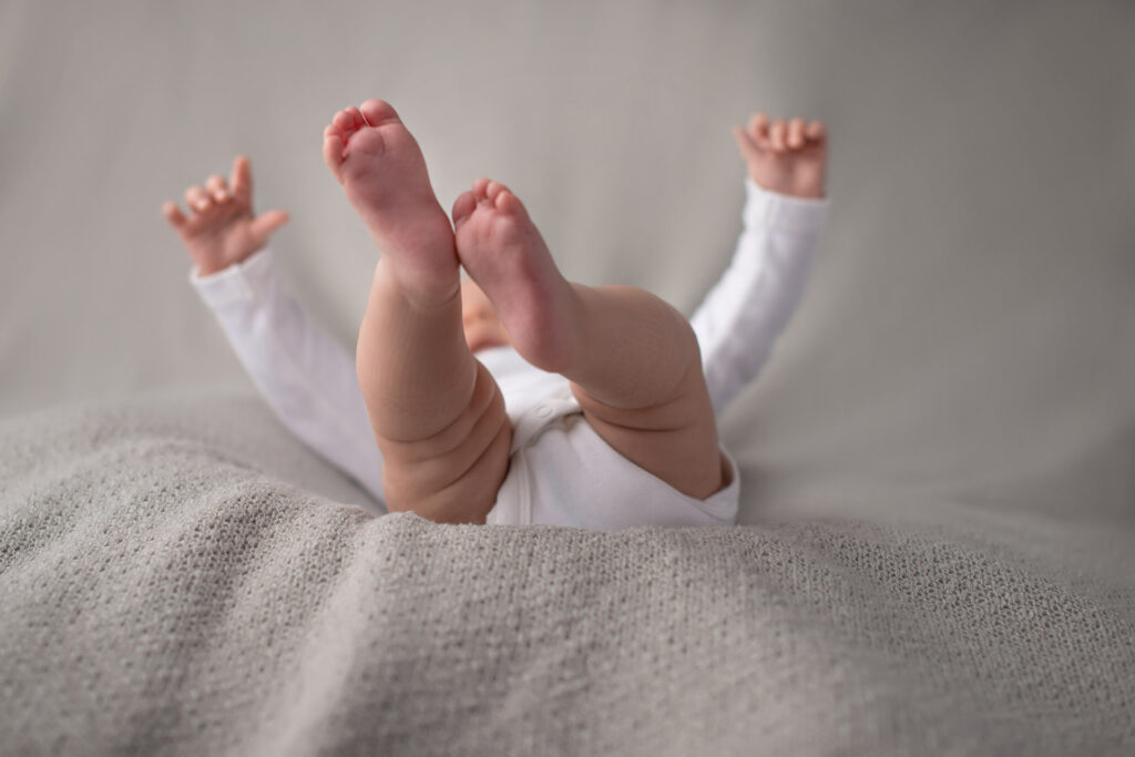 Baby strampelt fröhlich mit Beinen und Armen – Babyfotoshooting Ludwigsburg