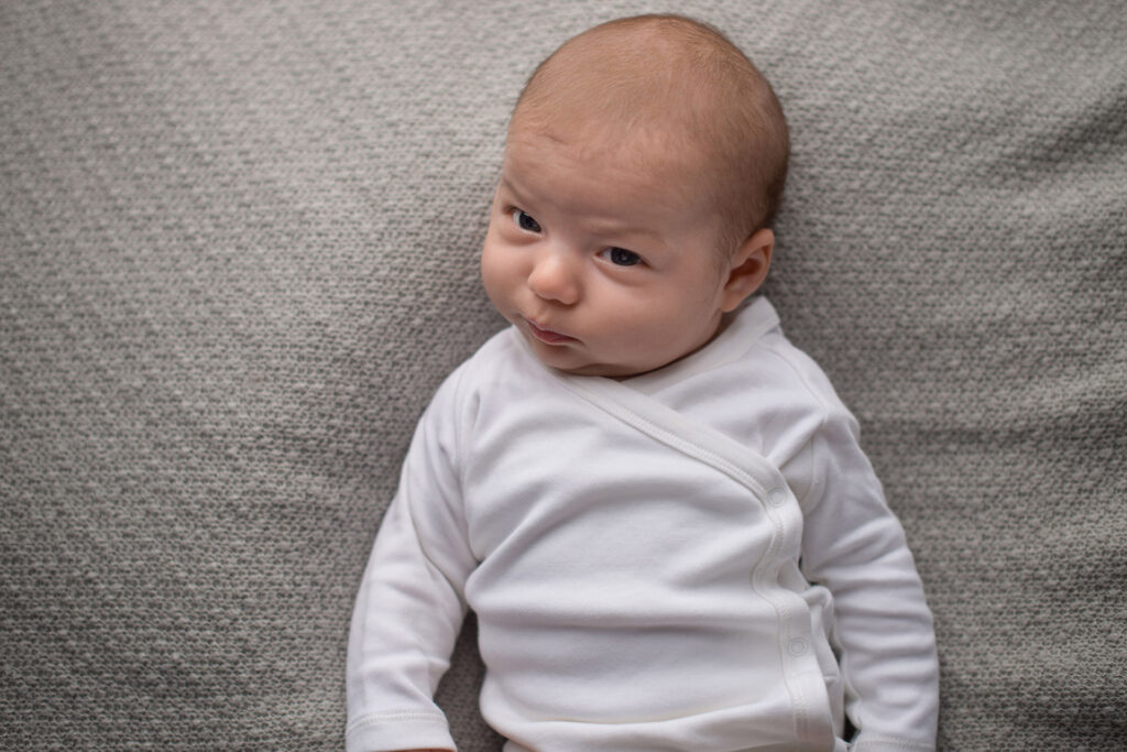 Baby liegt entspannt auf dem Rücken und schaut zur Seite – Babyfotoshooting Ludwigsburg