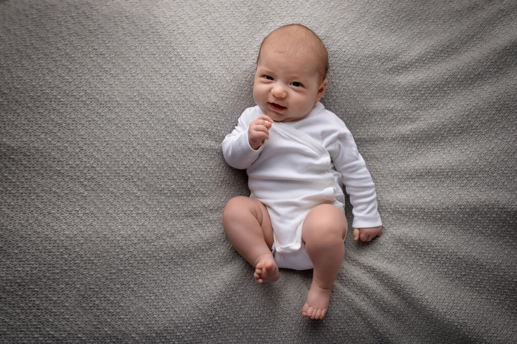 Baby liegt auf dem Rücken und lächelt – Babyfotoshooting Ludwigsburg