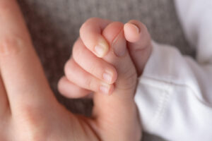 Kleine Babyhand auf buntem Strampler – Babyfotos Ludwigsburg