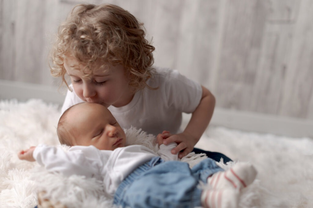 Die große Schwester küsst ihren Babybruder Newborn Shooting Ludwigsburg