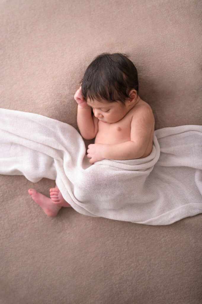 Baby liegt auf der Seite von einem Tuch bedeckt