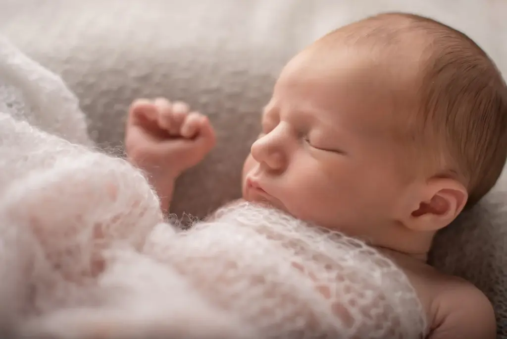 Schlafendes Baby in Rückenlage auf hellem Untergrund, Neugeborenenfotografie Eberdingen