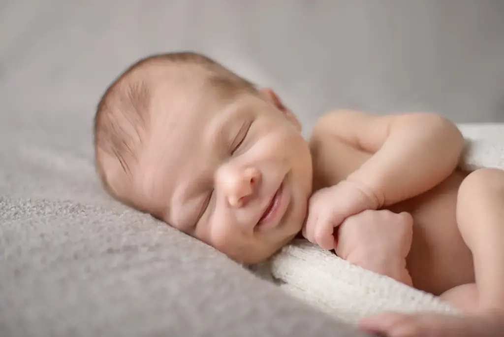 Neugeborenes Baby schlafend, in weißes Tuch gehüllt, Seitenansicht – Neugeborenenfotos Studio Hemmmingen
