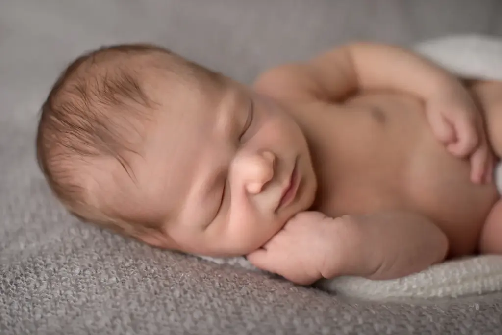 Neugeborenes auf der Seite liegend, Gesicht leicht zur Seite gedreht, schlafend – Babyfotografie Ludwigsburg