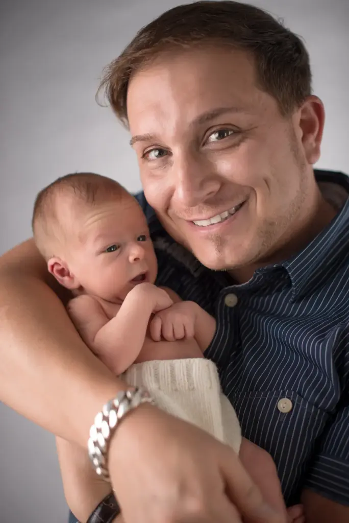 Lächelnder Papa hält Nevio zärtlich in den Armen – Elternfotos beim Neugeborenen-Fotoshooting Hemmingen